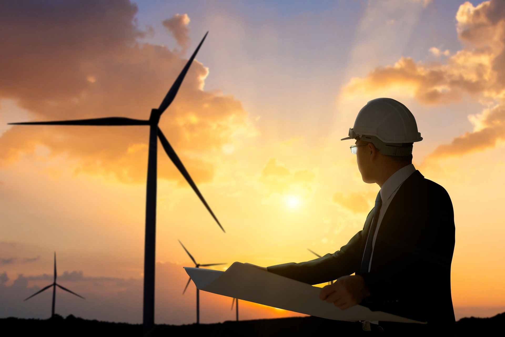 Engineer Evaluating Wind Turbine at Sunset